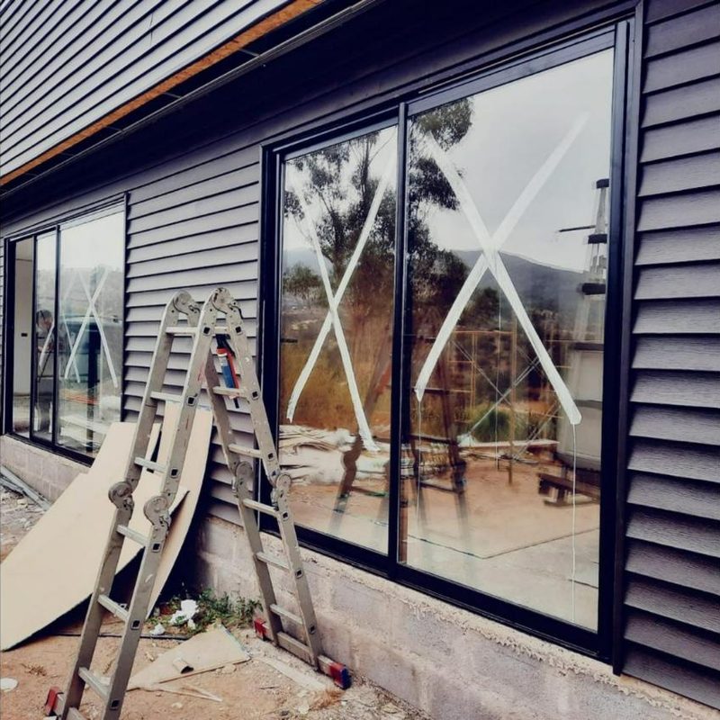 Ventanales negros de PVC con termopanel instalados en una casa con revestimiento gris